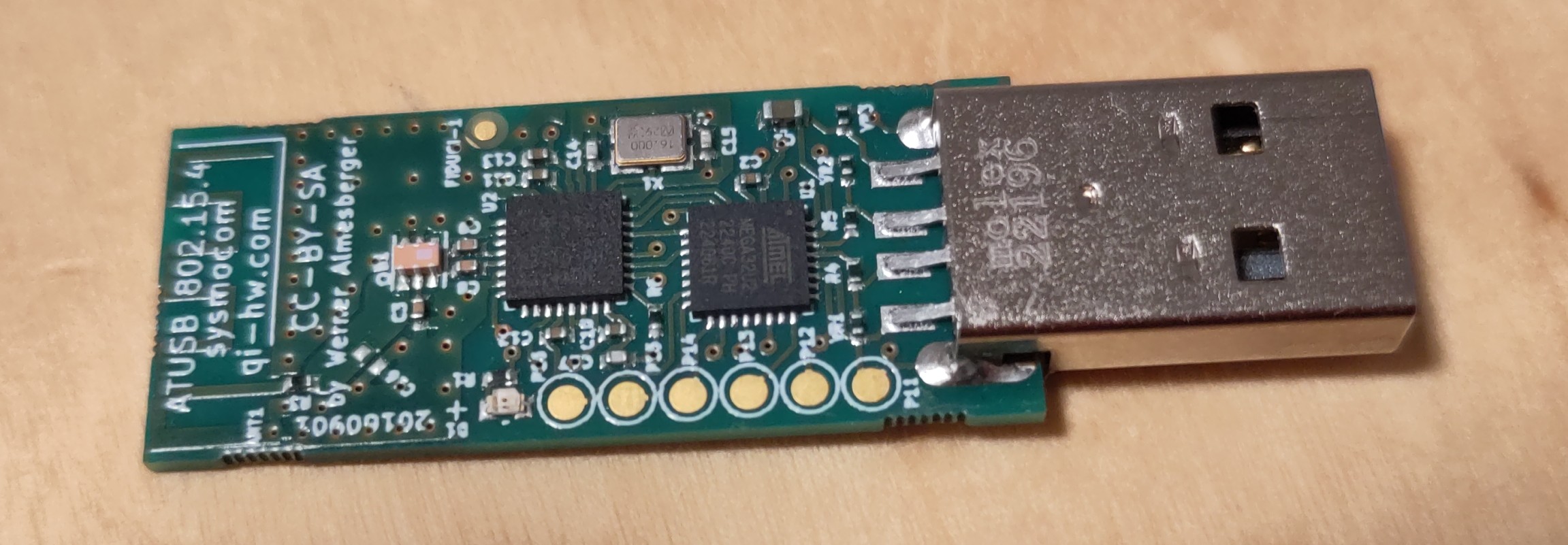 You can see a circuit board. There is a USB port on the right side. On the left side you can see an antenna built into the circuit board. Two distinctive black chips can be seen on the circuit board. The board itself is green.
